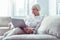 Modern retired woman holding silver laptop while watching video