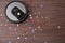 Modern robotic vacuum cleaner removing confetti from wooden floor. Space for text