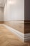 Modern room interior with wooden floor and white wall. Baseboard and wood paneling on the walls.