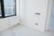 A modern room renovation with white walls and radiator, and a black window frame. Incomplete installation of electrical sockets,