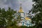 modern russian orthodox church dome and cross through leaves of trees  State historic cultural park  Busha  Ukraine