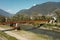 Modern rusted pedestrian and bicycle bridge with flowing Ticino river below. Beautiful panorama of the Alps of Italian Switzerland