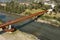 Modern rusted pedestrian and bicycle bridge with flowing Ticino river below. Beautiful panorama of the Alps of Italian Switzerland