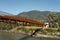 Modern rusted pedestrian and bicycle bridge with flowing Ticino river below. Beautiful panorama of the Alps of Italian Switzerland