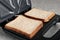 Modern sandwich maker with bread slices on grey table, closeup