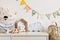 The modern scandinavian newborn baby room with copy space, wooden car, plush toys and clouds. Hanging cotton flags and white stars