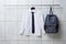Modern school uniform and backpack hanging on color wall