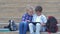 Modern schoolkids, little girl and small boy use digital tablet sitting on steps near backpacks during recess outdoor