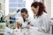 Modern scientist working with pipette in biotechnology laboratory equipment for research on a white table and an assistant who re