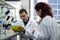 Modern scientist working with pipette in biotechnology laboratory equipment for research on a white table and an assistant who re