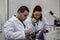 Modern scientist working with pipette in biotechnology laboratory equipment for research on a white table and an assistant who re