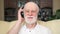 Modern senior man listening music with wireless headphones. Pensioner meloman dancing to music