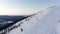 Modern ski resort chairlift moves over tracks against forest