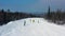 Modern ski resort in pine forest aeria, view from above. Footage. Young group of people snowboarding and skiing down the