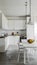 Modern, sleek kitchen with white surfaces, pendant lights, fruit bowl, and polished concrete floors.