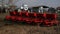Modern sowing seeds machine. Farmer tractor seeding. Red combine plow. Sowing crops at agricultural fields in spring