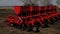 Modern sowing seeds machine. Farmer tractor seeding. Red combine plow. Sowing crops at agricultural fields in spring