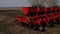 Modern sowing seeds machine. Farmer tractor seeding. Red combine plow. Sowing crops at agricultural fields in spring