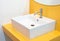 Modern square sink in the bathroom and yellow wall