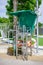 Modern stainless lifeguard chair with green roof around swimming pool