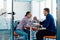 In a modern startup office, a businessman and a businesswoman business colleagues engage in a symbolic arm-wrestling