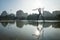 Modern statue of waterman with trident and lightened head in pond at Turia River Park, Valencia, Spain