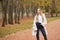 Modern street collection. Young blonde confident girl wearing white shirt, black jeans, trendy autumn coat and leather black boots