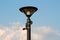 Modern street lamp post with LED lightning and surveillance camera with motion detector on cloudy blue sky background