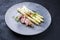 Modern style fried Iberian pork fillet sliced with blanched white asparagus and herbs with spice on a design plate