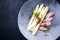 Modern style fried Iberian pork fillet sliced with blanched white asparagus and herbs with spice on a design plate