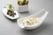 Modern style German remoulade with gherkin and cappers in a design bowl on a gray board