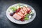 Modern style gourmet duck breast filet with rocket salad and cranberry relish on a design plate