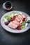 Modern style gourmet duck breast filet with rocket salad and cranberry relish on a design plate