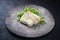 Modern style gourmet fried European skrei cod fish filet with purslane lettuce and herbs on a rustic design plate