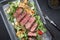 Modern Style Italian tagliata di manzo with lamb salad and dry aged sliced roast beef in a design skillet