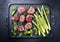 Modern style traditional barbecue Iberian pork filet medaillons with green asparagus and chili on a design cast iron tray