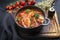 Modern style traditional Brazilian fish stew moqueca baiana with fish filet in tomato sauce in a design cast-iron roasting dish