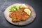 Modern style traditional deep-fried schnitzel with potato and cucumber salad on a rustic design plate
