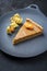 Modern style traditional French Tarte au citron piece with orange and physalis fruit on a design plate