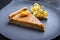 Modern style traditional French Tarte au citron piece with orange and physalis fruit on a modern design plate