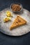 Modern style traditional French Tarte au citron piece with orange and physalis fruit on a rustic design plate