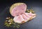 Modern style traditional German boiled Christmas ham with exotically spices on a black board