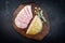 Modern style traditional German boiled Christmas ham with exotically spices and sage on a wooden design board