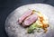 Modern style traditional gourmet duck breast filet with mashed potatoes and orange sauce on a rustic design plate