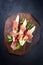 Modern style traditional Italian antipasti with prosciutto di Parma and honeydew melon slices on a wooden design board