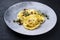 Modern style traditional Italian ravioli pasta offered with capers and onion chili pesto on a modern design plate