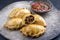 Modern style traditional South American empanada de carne offered with a chili dip on a rustic design plate