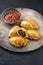 Modern style traditional South American empanada de carne offered with a chili dip on a rustic design plate