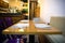 Modern styled wooden tables with plates forks, knives, napkins  and purple chairs in the kitchen
