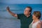 Modern sweet and loving hispanic mature couple taking selfie portrait- senior retired husband and wife on their 70s enjoying beach
